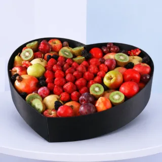Healthy seasonal exotic fruit gift arranged in a black heart-shaped box, perfect for sending care and get-well-soon wishes.