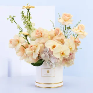 Peach Blossom Hat Box featuring peach roses, white matthiola, peach gerberas, and light pink hydrangeas beautifully arranged in a premium white flower hat box.