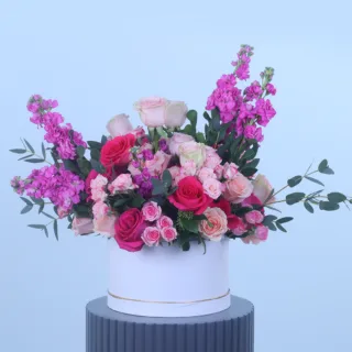 Pink Romance Floral Hat Box featuring fresh light pink roses, dark pink roses, pink spray roses, pink matthiola, skimmia, and parvifolia foliage beautifully arranged in a premium white hat box for gifting and special occasions.