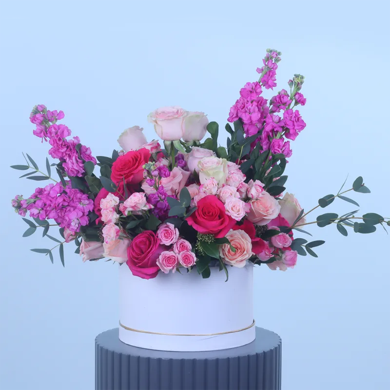 pink-romance-floral-hat-box Pink Romance Floral Hat Box featuring fresh light pink roses, dark pink roses, pink spray roses, pink matthiola, skimmia, and parvifolia foliage beautifully arranged in a premium white hat box for gifting and special occasions.