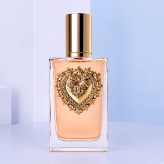 D&G Devotion Intense EDP For Women 100ML perfume bottle displayed beside matching cream packaging, featuring the signature Sacred Heart design and warm peach-toned fragrance inside an elegant glass bottle.