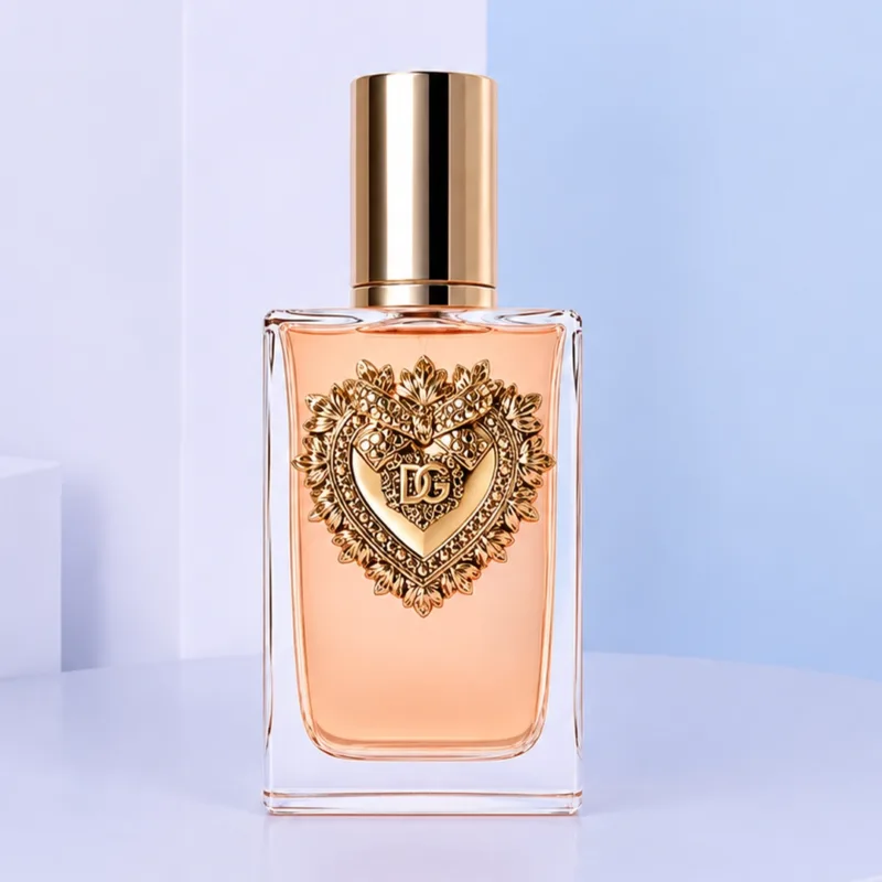 dg-devotion-intense-edp-for-women-100ml D&G Devotion Intense EDP For Women 100ML perfume bottle displayed beside matching cream packaging, featuring the signature Sacred Heart design and warm peach-toned fragrance inside an elegant glass bottle.