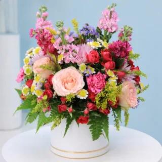 Fresh mixed flower arrangement with roses and seasonal blooms beautifully presented in an elegant white hat box.