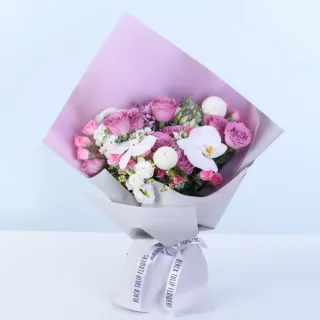 Purple Rose & Phalaenopsis Bouquet featuring purple roses, white phalaenopsis blooms, pink spray roses, white matthiola, white lisianthus, tanacetum, and premium floral wrapping.