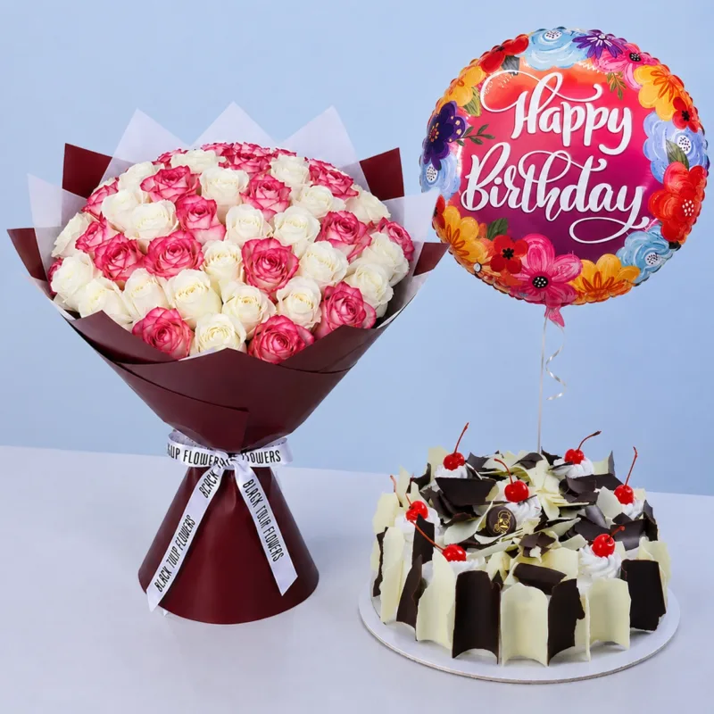 rose-harmony-black-white-forest-cake Rose Harmony Black & White Forest Cake featuring a bouquet of fresh double pink and white roses, a Happy Birthday balloon, and a 1 kg Black & White Forest Cake for birthday celebrations.