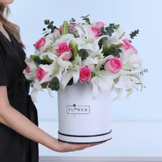 Gentle Grace featuring pink roses, pink Oriental lilies, and Baby Blue eucalyptus arranged in a white hatbox.