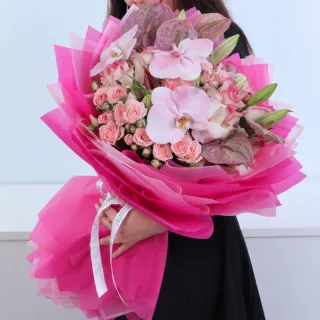 Pastel Dreams bouquet featuring peach spray roses, pink double roses, light pink anthuriums, pink Oriental lilies, and light pink Phalaenopsis orchid blooms beautifully arranged.