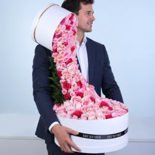 Love Unfolded bouquet with pink, peach, and dark pink roses arranged in a dramatic cascading design, creating a luxurious romantic floral gift for special occasions.