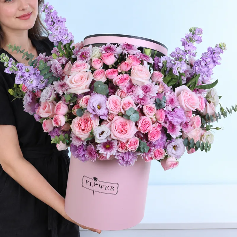Pink Twilight flower box featuring light pink roses, peach Sweet Sara baby roses, pink Dinara baby roses, Malibu chrysanthemums, purple matthiola, lisianthus, and eucalyptus.