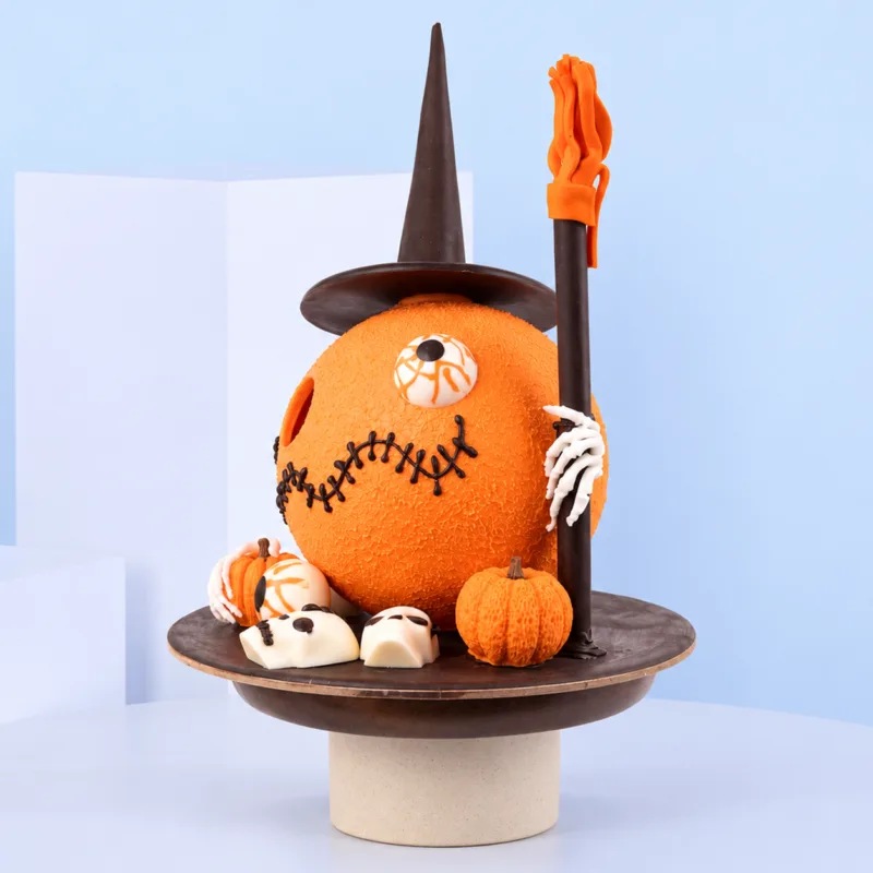 Smashable Spooky Witch Chocolate featuring an orange witch character with a black pointed hat, chocolate staff, skeleton hand, and pumpkin decorations on a chocolate base.