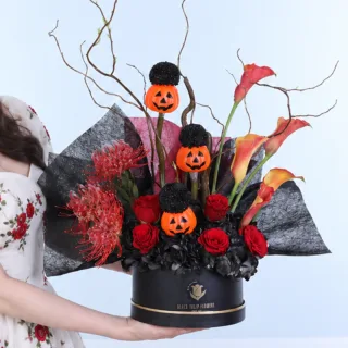 Wicked Pumpkin Garden Halloween arrangement featuring five orange calla lilies, seven red roses, three painted Ping Pong flowers, two painted hydrangeas, and Cordifolium foliage with pumpkin decorations.