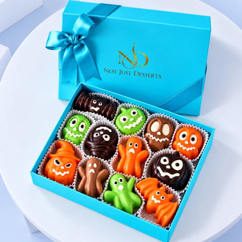 Yummy Trick or Treat Halloween Choco Box featuring colourful ghost, pumpkin, mummy, and monster-shaped filled chocolates in a blue gift box.