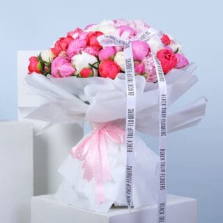 BTF Home 59 A large bouquet of pink and white peonies wrapped in white paper, tied with a pink ribbon.