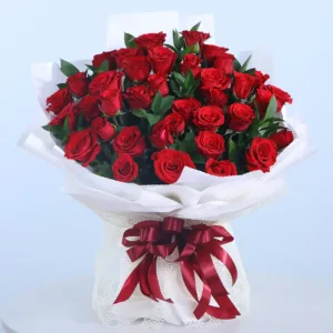 Why UAE Celebrates Mother’s Day in March: A Cultural Insight 2 A lush bouquet of red roses is presented in a white paper wrapping, tied with a deep red ribbon.