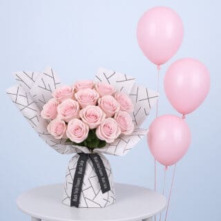 BTF Home 70 A bouquet of light pink roses wrapped in white paper with a black geometric pattern along with pink balloons.